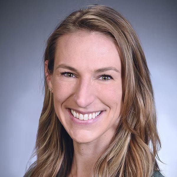 Professional headshot of a smiling woman with long hair.