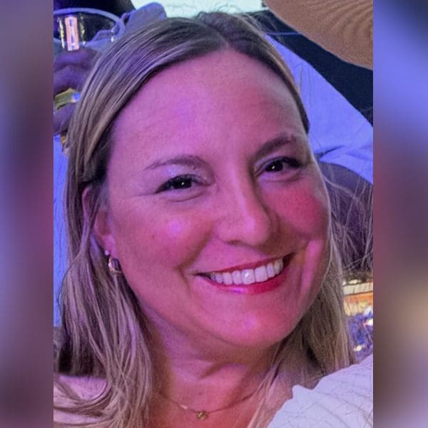 Smiling woman with blonde hair at an outdoor evening event.