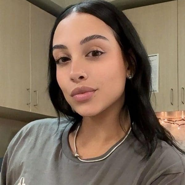 A woman with long dark hair poses in a kitchen.